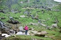 Young smiling female tourist standing near tent on green rocky meadow in mountains in Romania Royalty Free Stock Photo