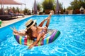 Young smiling fitted girl in bikini, straw hat relax on inflatable swan in swimming pool. Attractive woman in swimwear Royalty Free Stock Photo