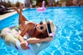 Young smiling fitted girl in bikini, straw hat relax on inflatable swan in swimming pool. Attractive woman in swimwear Royalty Free Stock Photo