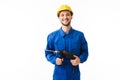 Young smiling foreman in blue uniform and yellow helmet joyfully looking in camera holding drilling machine in hands Royalty Free Stock Photo