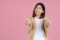 Young smiling fun happy woman of asian showing thumb up like gesture blink isolated on pink background studio portrait. People