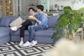 Young smiling gay couple having popcorn while watching TV in the living room at home, LGBTQ and diversity concept Royalty Free Stock Photo