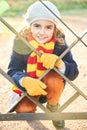 young smiling girl in blue coat behind metal bars in the park in autumn Royalty Free Stock Photo