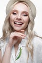 Young smiling girl with curls in a hat. A beautiful model in a white shirt and a brooch-flower Royalty Free Stock Photo