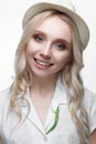 Young smiling girl with curls in a hat. A beautiful model in a white shirt and a brooch-flower Royalty Free Stock Photo