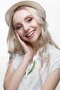 Young smiling girl with curls in a hat. A beautiful model in a white shirt and a brooch-flower Royalty Free Stock Photo