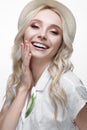 Young smiling girl with curls in a hat. A beautiful model in a white shirt and a brooch-flower Royalty Free Stock Photo