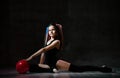 Young smiling girl gymnast with long hair in black sport body and uppers sitting on floor near pink gymnastic ball