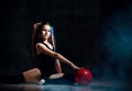 Young smiling girl gymnast with long hair in black sport body and uppers sitting on floor near pink gymnastic ball