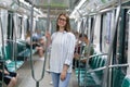 Young smiling girl inside subway car hold on handrail. Cheerful student female travel in underground Royalty Free Stock Photo