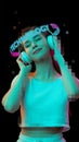 Young smiling girl with neon lettering around head listening music isolated over black background
