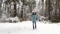 Young smiling girl recreation at snowy forest. Happy woman enjoying beautiful winter day at pine woodland. Cheerful lady