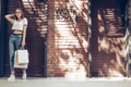 Young smiling girl with shopping bag wearing white t-shirt and blue jeans near brick wall.Lifestyle concept. Royalty Free Stock Photo