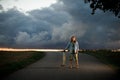 Young smiling girl standing in the middle of an asphalt road holding her longboard Royalty Free Stock Photo