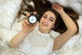 Young smiling girl turns off the alarm clock. ahead of a fun weekend Royalty Free Stock Photo