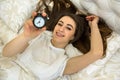 Young smiling girl turns off the alarm clock. ahead of a fun weekend Royalty Free Stock Photo