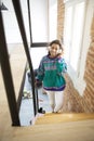 Young, smiling girl walking up the stairs inside her house. She is wearing a headphone