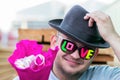 A young smiling guy in dark glasses with the inscription love gives a bouquet of flowers and takes off his hat in greeting Royalty Free Stock Photo