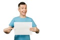 Young smiling guy dressed in a blue t-shirt holds a sheet of paper of A4 on a isolated white background Royalty Free Stock Photo