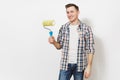 Young smiling handsome man in casual clothes holding paint roller for wall painting isolated on white background Royalty Free Stock Photo