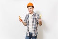 Young smiling handsome man in casual clothes and protective orange hardhat holding toy hammer and saw isolated on white Royalty Free Stock Photo