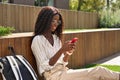 Young happy African woman university student model using mobile phone outdoors. Royalty Free Stock Photo