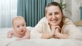 Young smiling happy mother lying with her baby in bed and looking in camera. Concept of parenting ,baby care and family Royalty Free Stock Photo