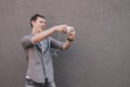 Young smiling hipster man taking selfie with his smartphone. Gray background, copy space