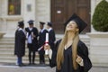 Young smiling joyful girl student in a university graduate gown and diploma in her hands. Royalty Free Stock Photo