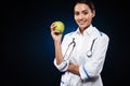 Young smiling lady doctor holding apple and looking camera isolated Royalty Free Stock Photo