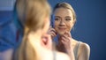Young smiling lady looking at mirror reflection, happy with skin treatment Royalty Free Stock Photo