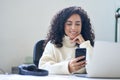 Young smiling latin business woman using phone in office sitting at desk. Royalty Free Stock Photo