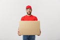 Young smiling logistic delivery man in red uniform holding the box on white background