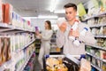Young smiling male customer choosing milk and dairy products in supermarket Royalty Free Stock Photo