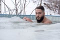Young smiling male having fun while swimming in an ice pool on a winter day Royalty Free Stock Photo
