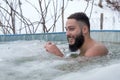 Young smiling male having fun while swimming in an ice pool on a winter day Royalty Free Stock Photo