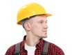 Young smiling male worker in a construction worker, in a yellow helmet, working overalls and a red checkered shirt on a Royalty Free Stock Photo
