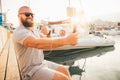 Young smiling man with beard is making selfie or video broadcast with smartphone on stabilizer or stabiliser and showing thumb up