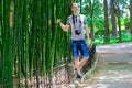 Young and smiling man with a camera stands near a high bamboo