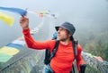 Young smiling man crossing canyon over Suspension Bridge and touching multicolored Tibetan Prayer flags hinged over gorge. Mera