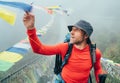 Young smiling man crossing canyon over Suspension Bridge and touching multicolored Tibetan Prayer flags hinged over gorge. Mera Royalty Free Stock Photo