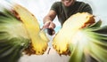 Young smiling man cutting pineapple - Close up male hand holding sharp knife preparing tropical fresh fruits Royalty Free Stock Photo