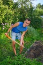 Young smiling man digging a garden bed for planting Apple trees Royalty Free Stock Photo