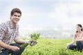 Young smiling man holding plant and gardening with young woman in a roof top garden Royalty Free Stock Photo
