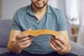 Young smiling man holding shoe orthopedic insole in his hands sitting on sofa at home.