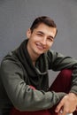 Young smiling man looking at camera against grey wall. Guy wearing casual clothing outdoors. Royalty Free Stock Photo