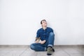 Young smiling man looking up sitting on the floor of new house with his cat. Royalty Free Stock Photo