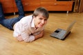 Young smiling man lying on the floor with laptop Royalty Free Stock Photo