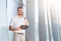 Young smiling man making a call and holding clipboard Royalty Free Stock Photo