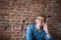 Young smiling man manager talking on mobile phone with colleague, sitting in modern office against wall with copy space. Royalty Free Stock Photo